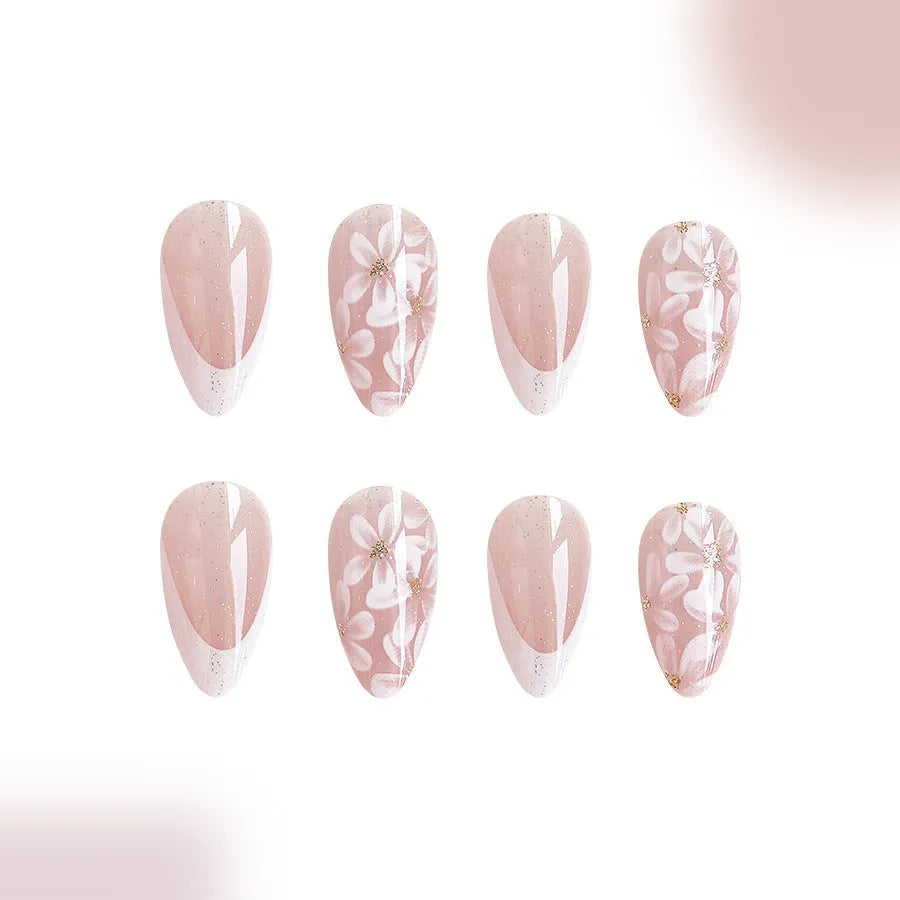 Short almond shaped false nails with French style gloss and glittering powder flower accents