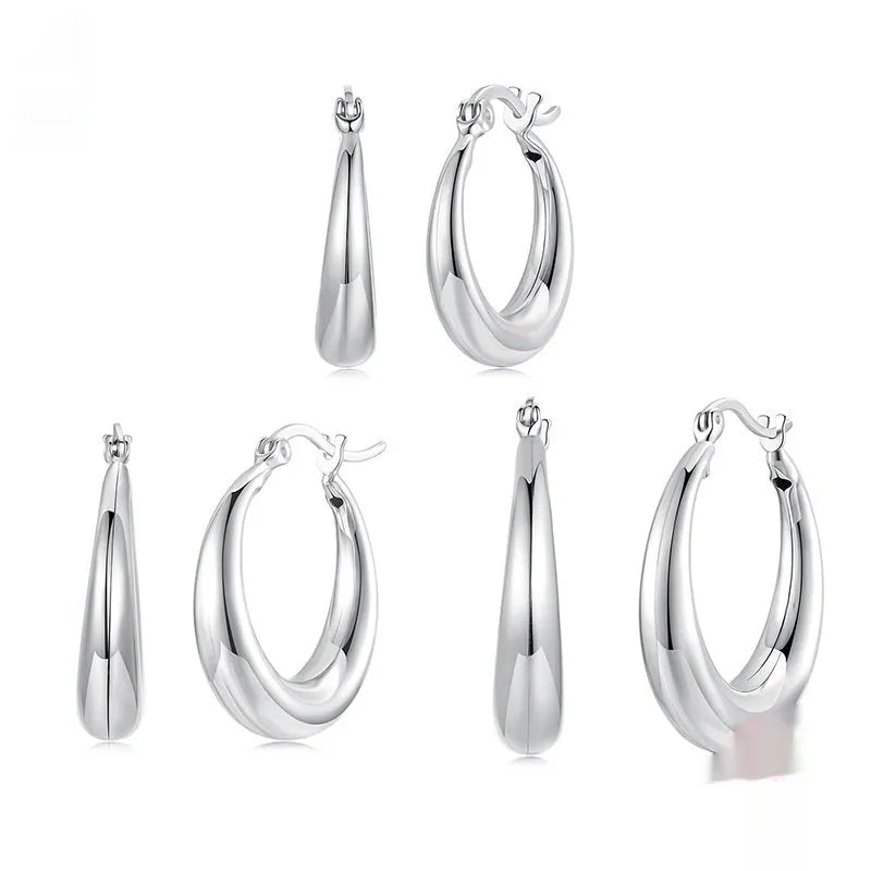 A pair of copper ring-shaped ear clip earrings with silver posts on a white background.
