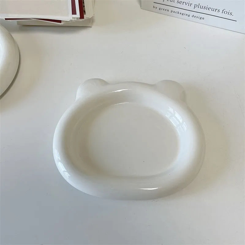 White round ceramic plate with bear doodle design, used as a saucer for a small succulent plant pot.