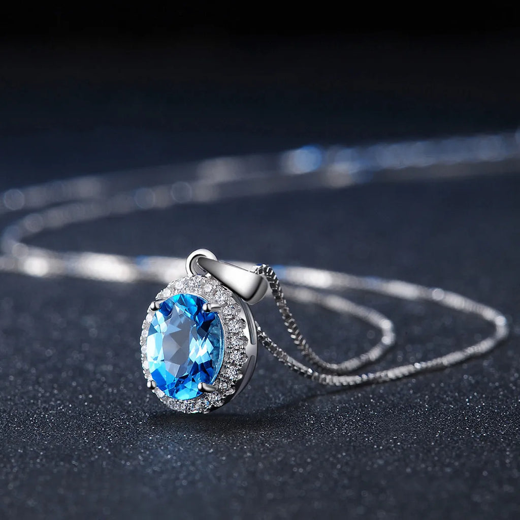 Women's sterling silver jewellery set with blue topaz gemstones in geometric design including earrings, ring, pendant, and necklace
