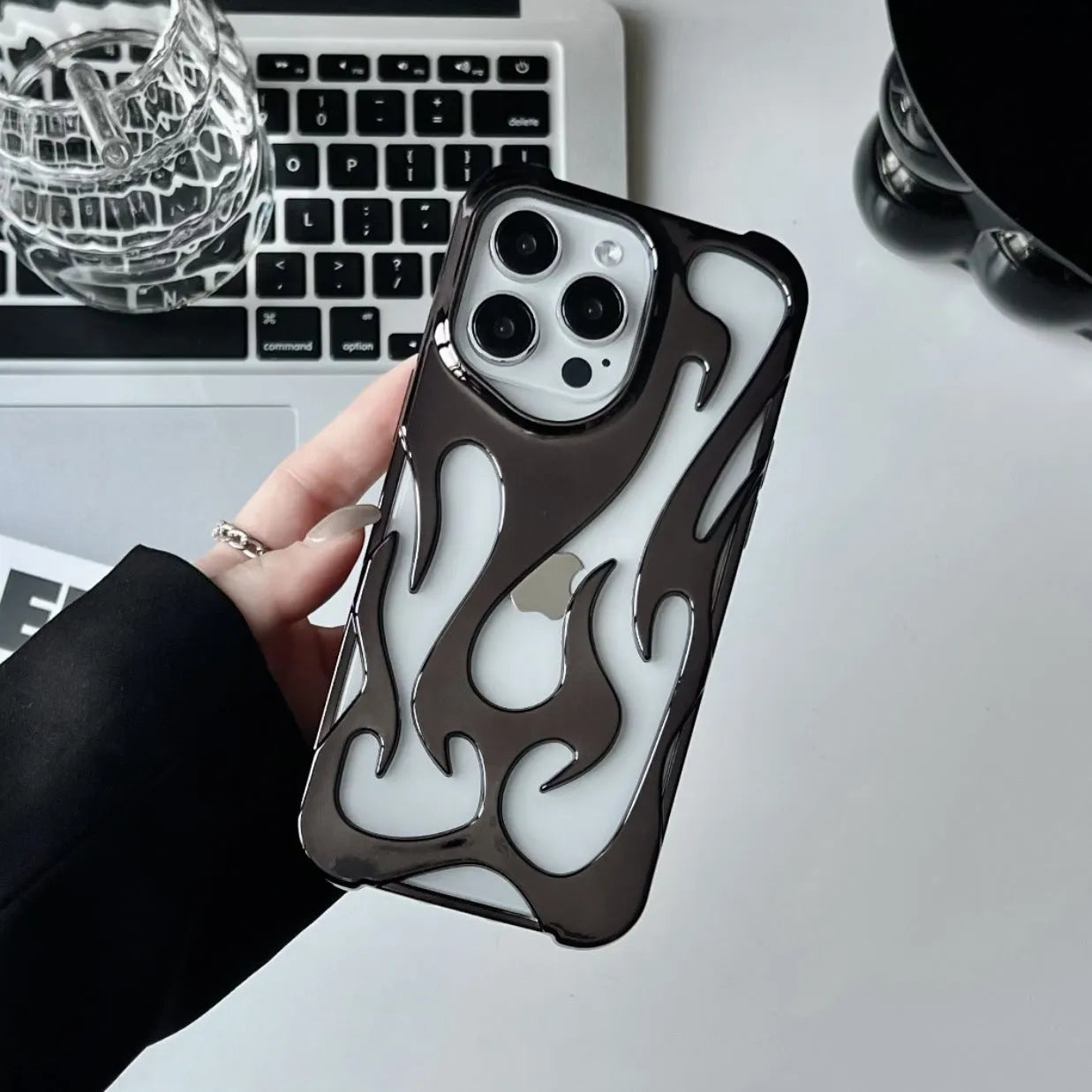 Electroplated hollow flame pattern TPU iPhone case in silver plating shown on a phone.