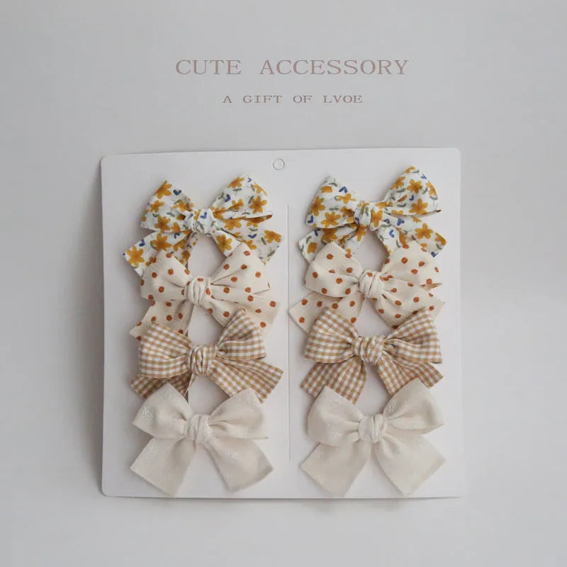 Set of eight fabric hairclips with dovetail bows in a chosen colour like beige grid dots or pink.
