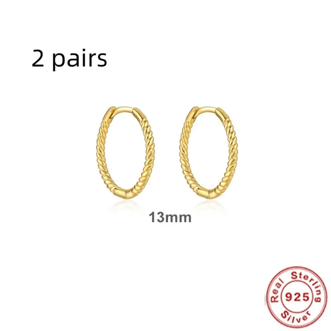 A pair of twisted sterling silver round earrings in a geometric design on a white background.