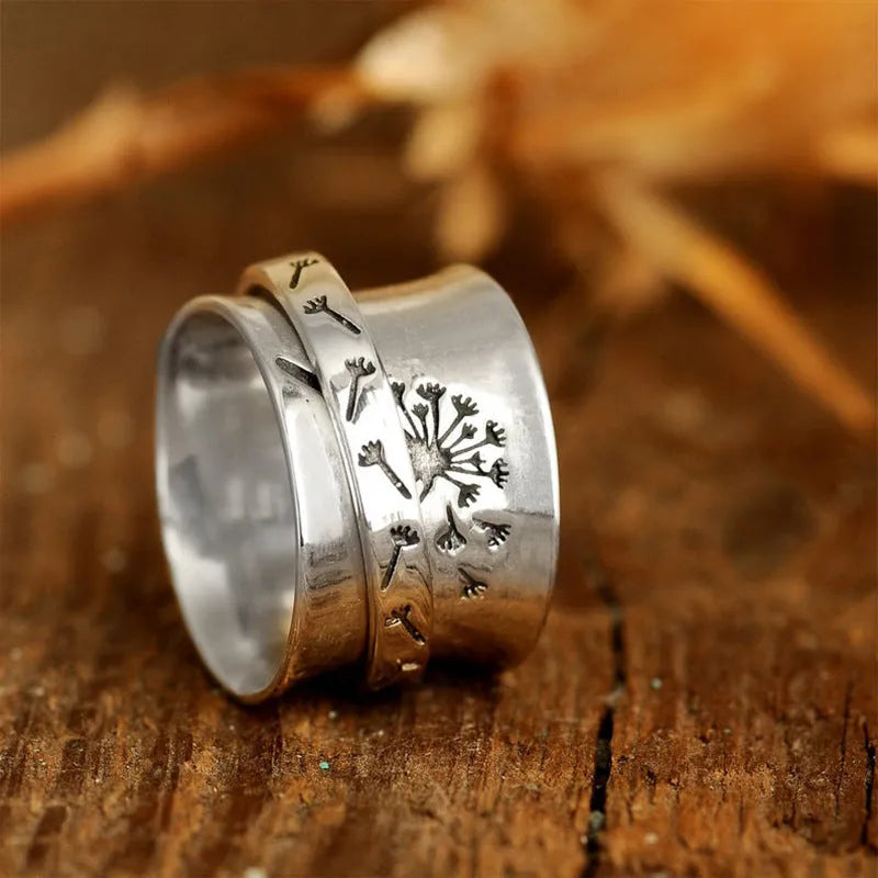 Silver electroplated alloy flower ring with rotating element on a hand.