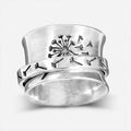 Silver electroplated alloy flower ring with rotating element on a hand.