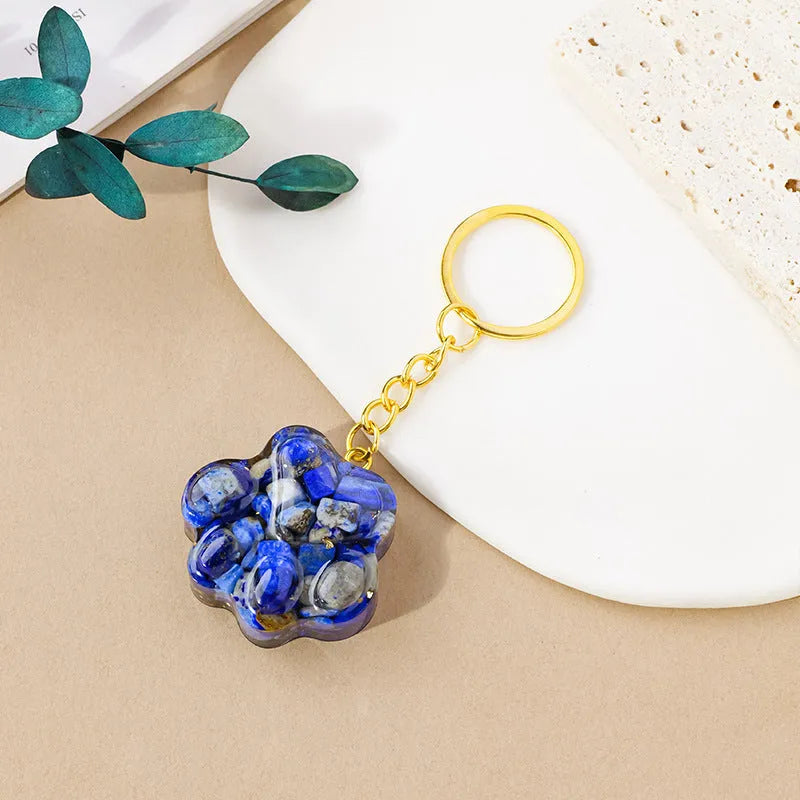 Natural crystal cat's paw shaped keychain charm on a keyring, showing colour variations of different gemstones.