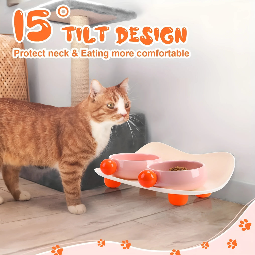 A pink ceramic raised pet bowl with two compartments and a non-slip black rubber base.