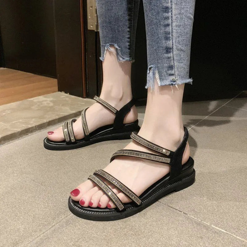 Women's flat sandals in gold with round toe, rhinestone decoration, and elastic band.