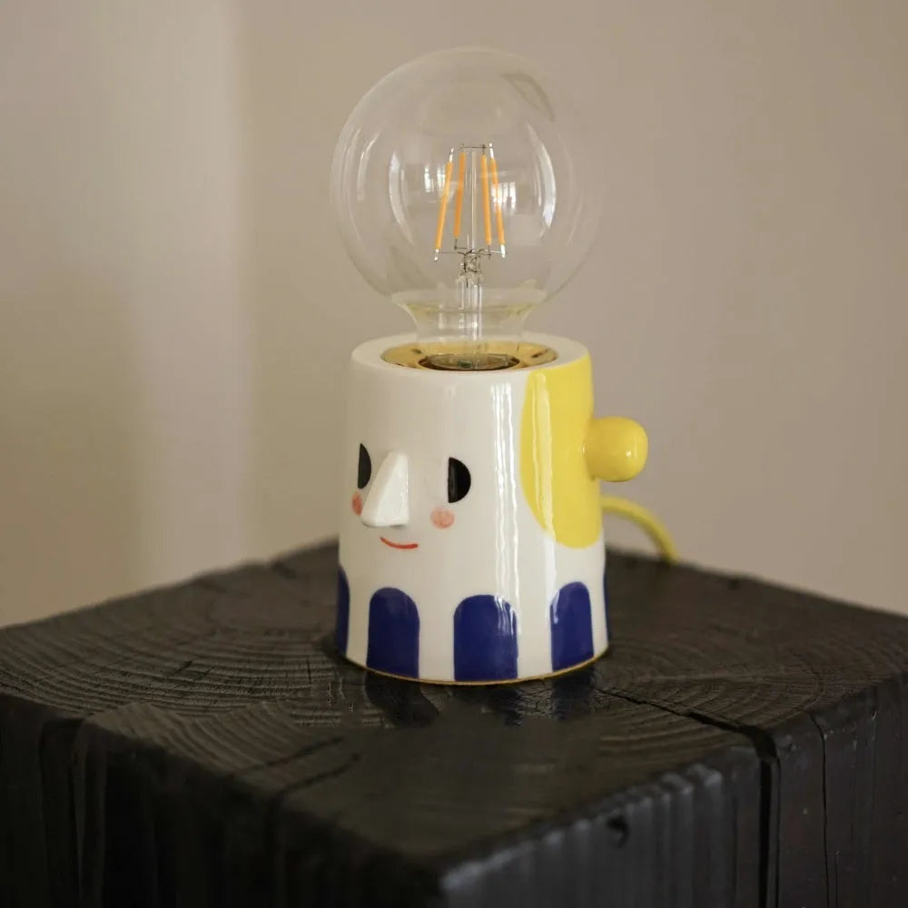 Handmade ceramic bedside lamp with a ball headlight design on a table.