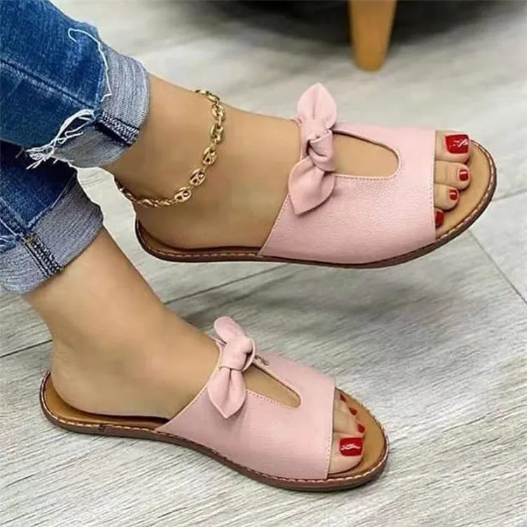 Ladies casual sandals with a bow detail and fish mouth slipper style in black, pink, or gold.
