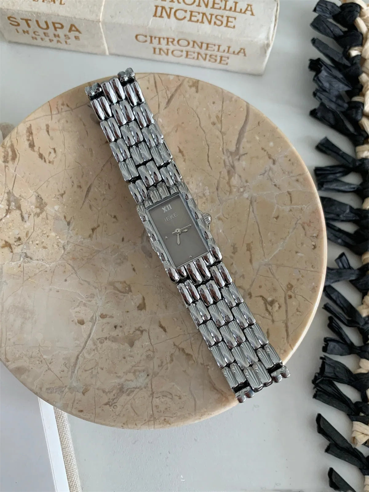 Women's bracelet-style watch with 15mm dial, silver stripe strap, and butterfly clasp