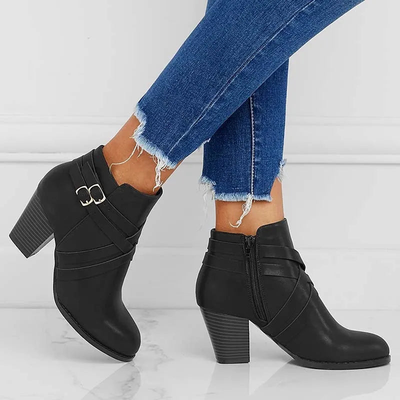Women's black short boot with 7cm heel, side zipper, belt buckle, and rubber sole