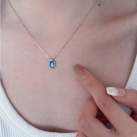 Geometric navy blue water drop pendant necklace on a model, showing the adjustable cross chain.