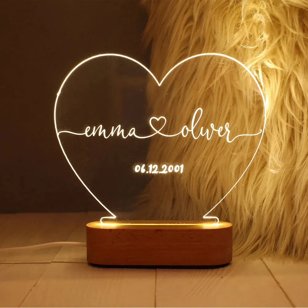 Custom transparent acrylic night light with engraved names and date, lit by LED base.