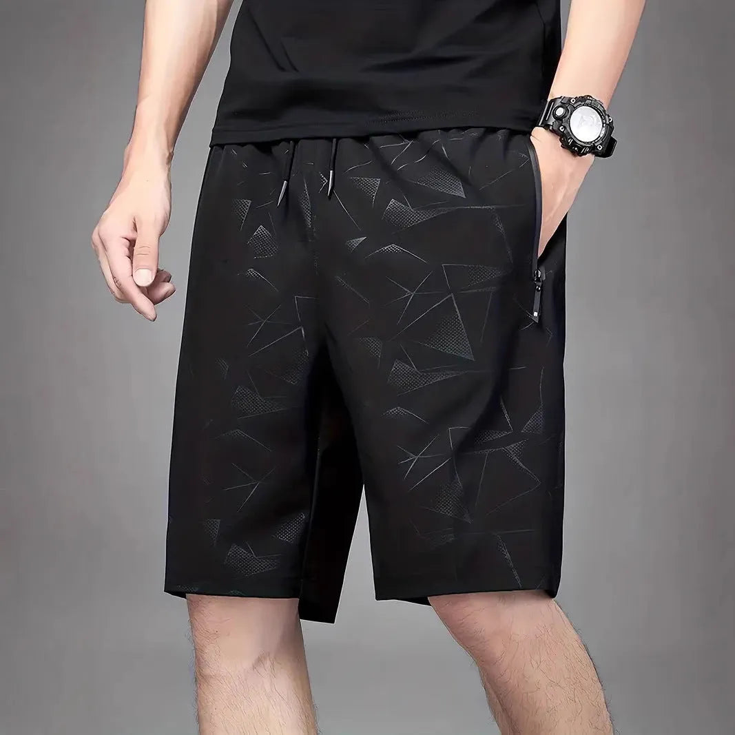 Man wearing loose grey polyester sports shorts on a beach.