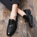 Men's black pointed toe slip on shoes with a gold tassel detail on the upper.
