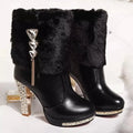 Women's black and white ankle boots with a chunky high heel on a solid colour background.