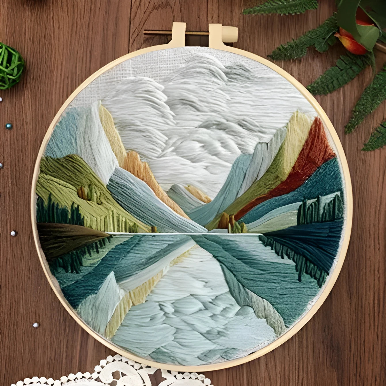 DIY embroidery kit with landscape-printed cotton fabric, embroidery hoop, needles, and coloured thread spools.