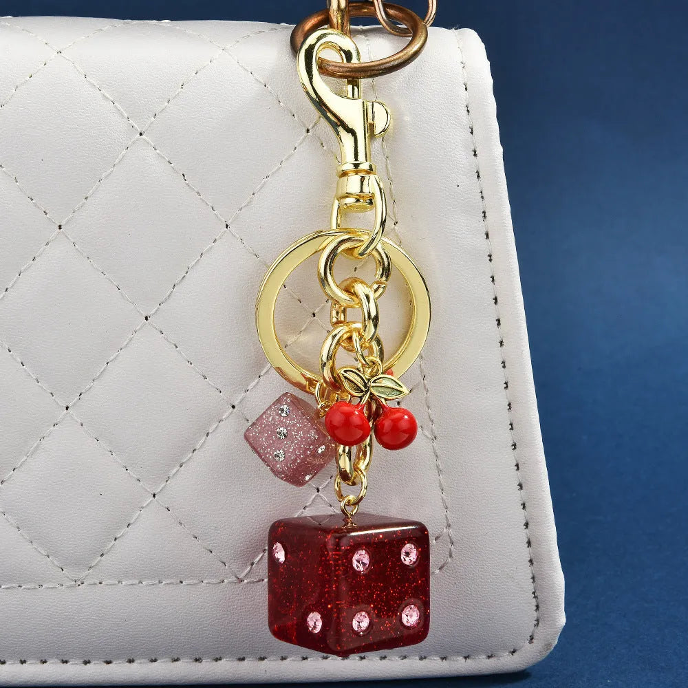 Square cherry two-tone dice keychain pendant on a metal ring.