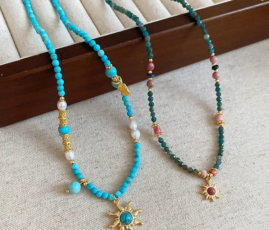 Sun necklace with a stone geometric pendant and freshwater pearls on a clavicle chain.
