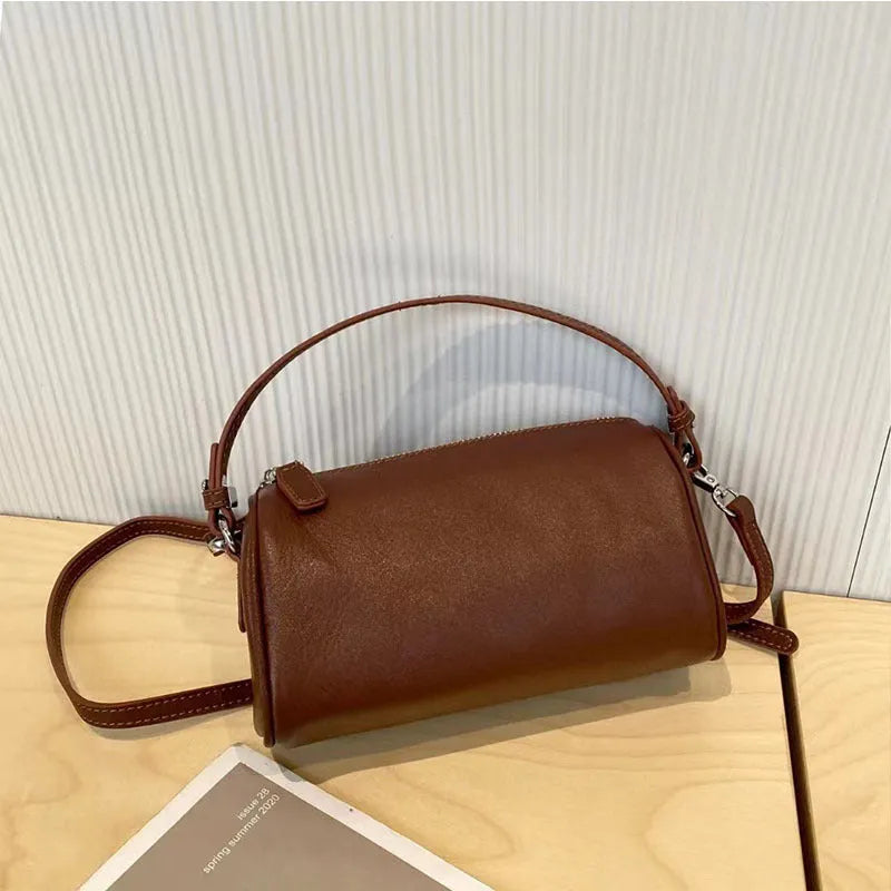 Soft genuine leather cylindrical crossbody bag in street style, shown in black, with a single strap.