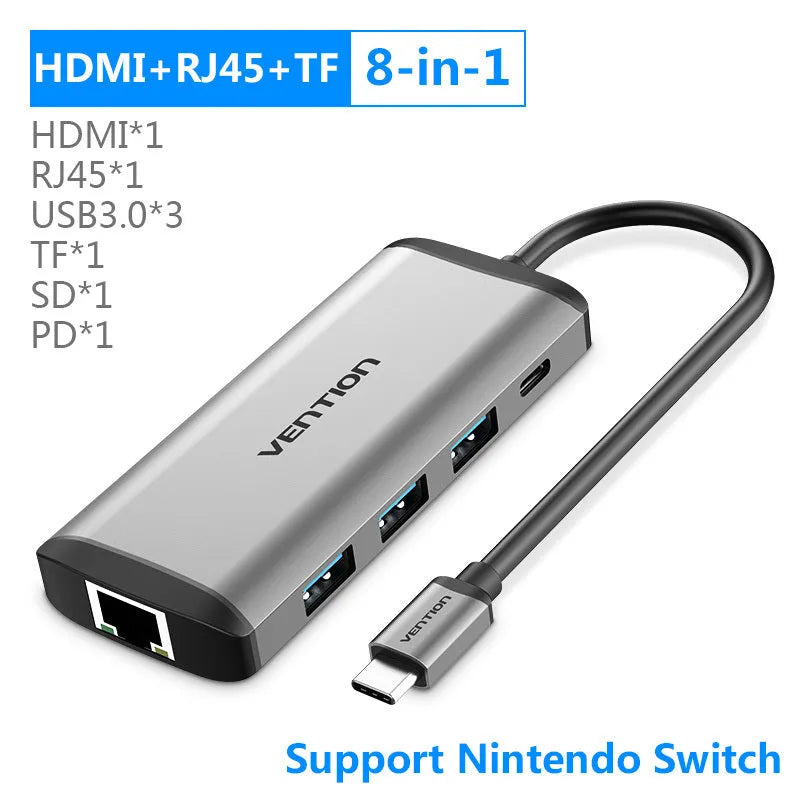 Deep grey USB-C multi-port hub with HDMI, three USB ports, Ethernet, and memory card slots on a desk.