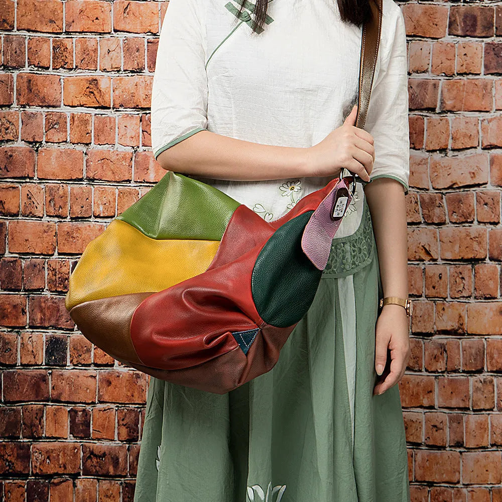 Brown cowhide leather travel bag with crossbody strap, shown next to a laptop and tablet.