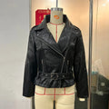 Black punk style short leather jacket with a Peter Pan collar and drawstring waist on a hanger.