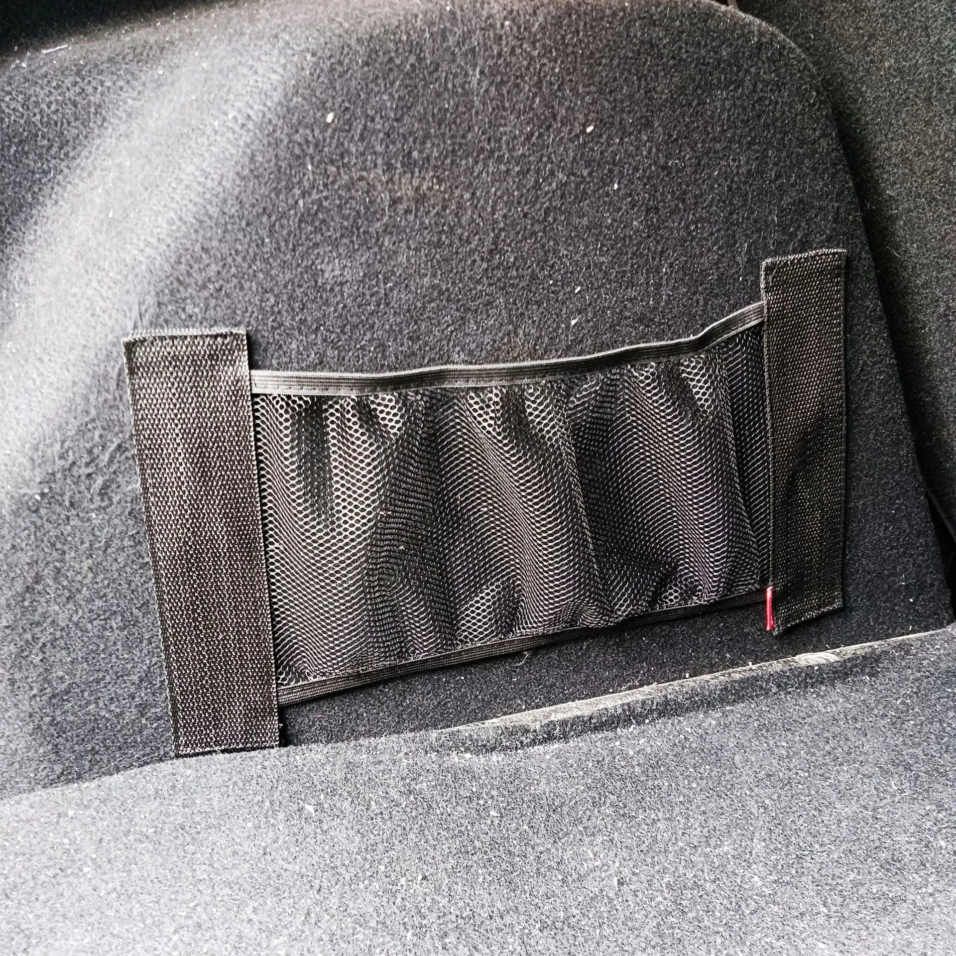 Elastic polyester car boot storage net shown holding shopping bags, available in 20x45cm or 20x35cm sizes.