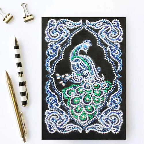 Black hardcover A5 diamond painting notebook with peacock beauty design, showing dimensions 142mm by 207mm.
