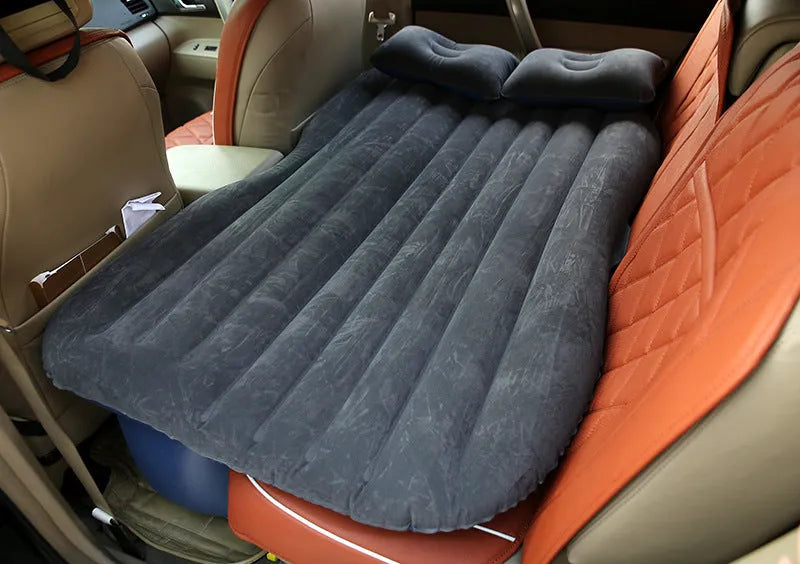 Black inflatable car bed with flocking surface and two pillows, shown folded next to a storage bag.