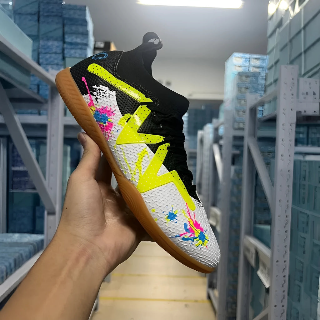 Men's black and yellow football boots with removable rubber studs on artificial grass