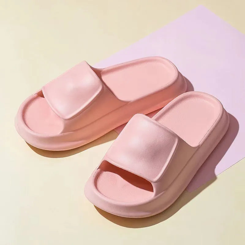 Pair of thick-soled white EVA foam flip-flop slippers on a bathroom floor, showing non-slip tread pattern.
