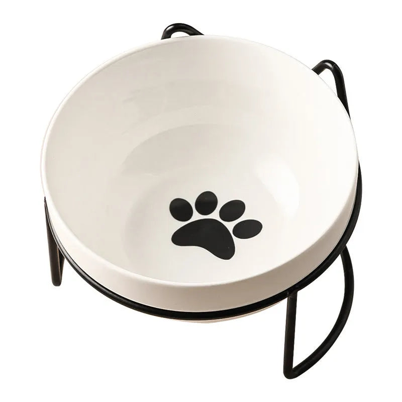 White ceramic cat bowl with decorative pattern sitting in a black iron frame stand.