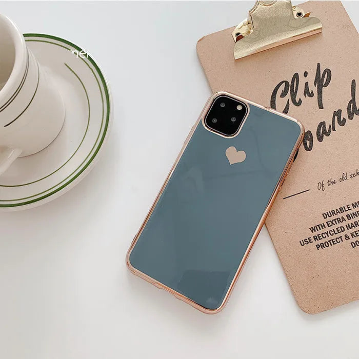 TPU iPhone case with solid colour and a raised metallic love heart design on the back.