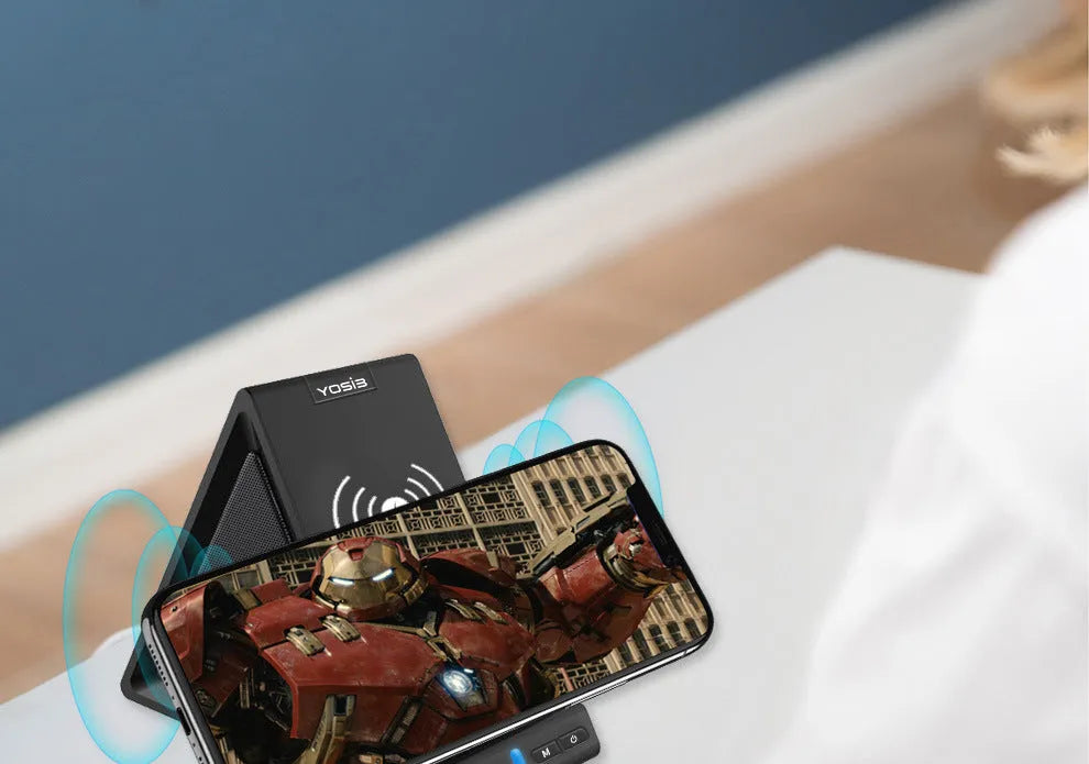 Black ABS Bluetooth speaker with integrated wireless charging pad and phone stand, shown on a desk.