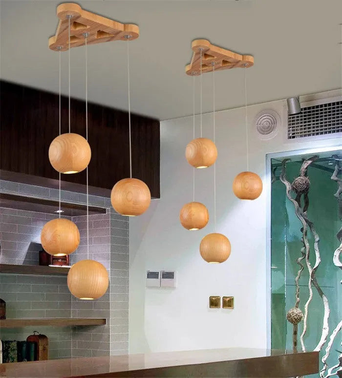 Nordic solid wood ball chandelier hanging lamp with adjustable cord over a dining table.