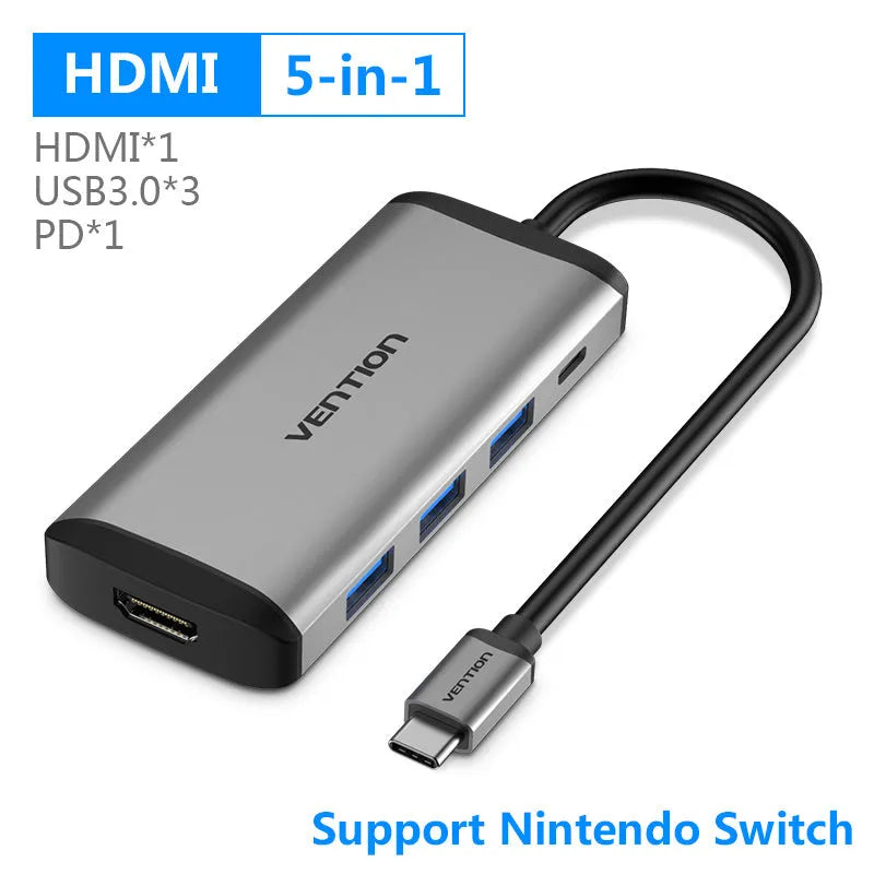 Deep grey USB-C multi-port hub with HDMI, three USB ports, Ethernet, and memory card slots on a desk.