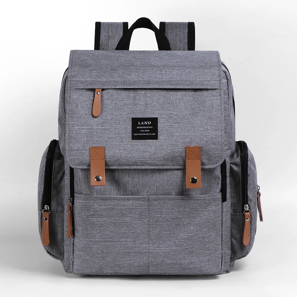 LAND Mommy large grey diaper backpack with changing mat, shown with baby care items.