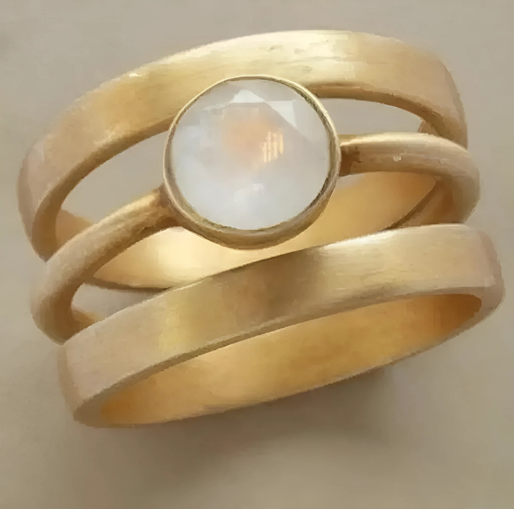 Gold geometric ring with a white chalcedony stone set using hollow micro-inlay technique.