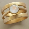 Gold geometric ring with a white chalcedony stone set using hollow micro-inlay technique.