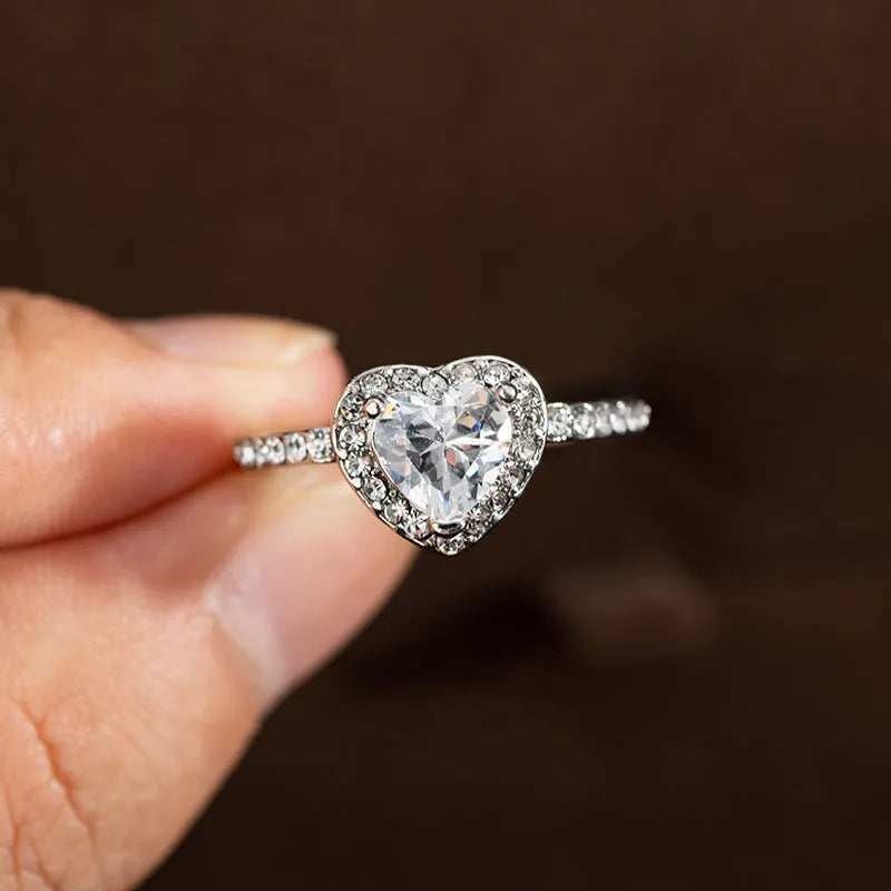 Heart-shaped women's ring with crystal decoration in rose gold or silvery finish on a size chart.