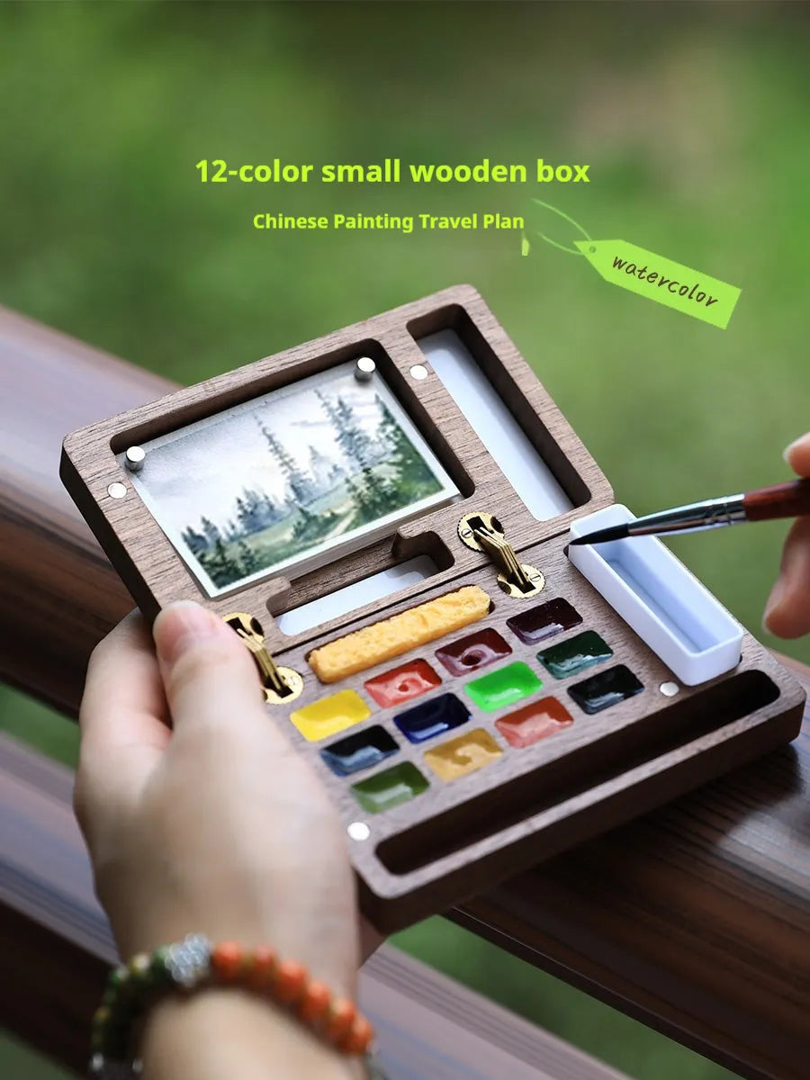 Mini walnut wooden watercolour paint box set with leather carry case, open to show professional artist pigments.