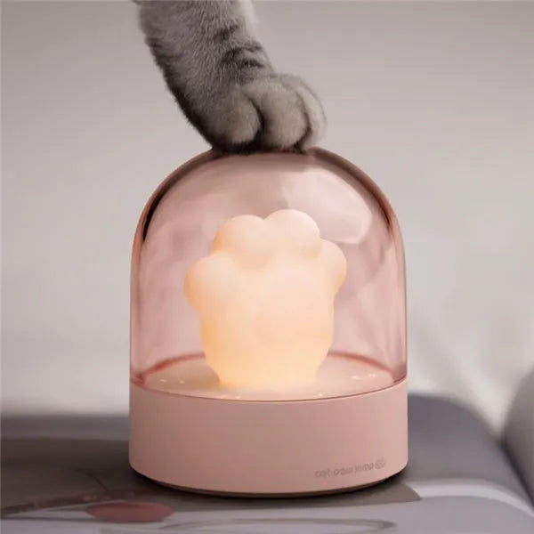 Pink and grey cat paw shaped USB night light with a music box feature on a desktop.