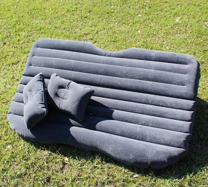 Black inflatable car bed with flocking surface and two pillows, shown folded next to a storage bag.