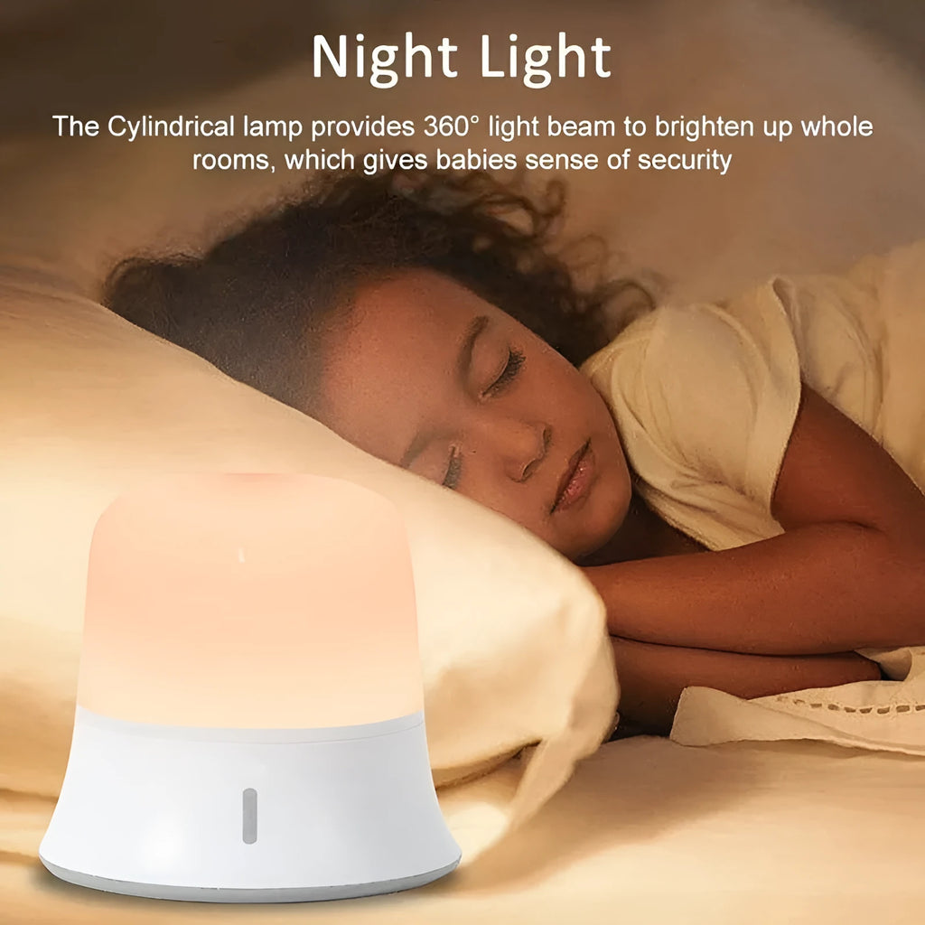 White cylindrical bedside night light with touch controls and motion sensor on a table.