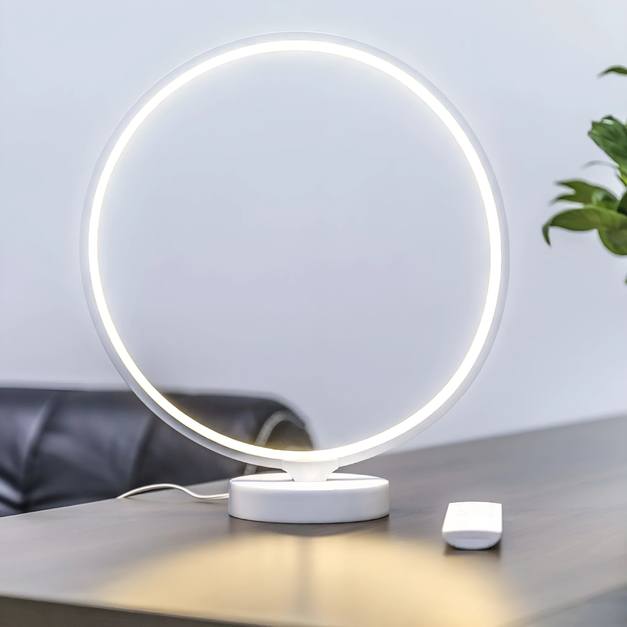 White spherical Full Moon Lamp with remote control on wooden table showing warm white glow