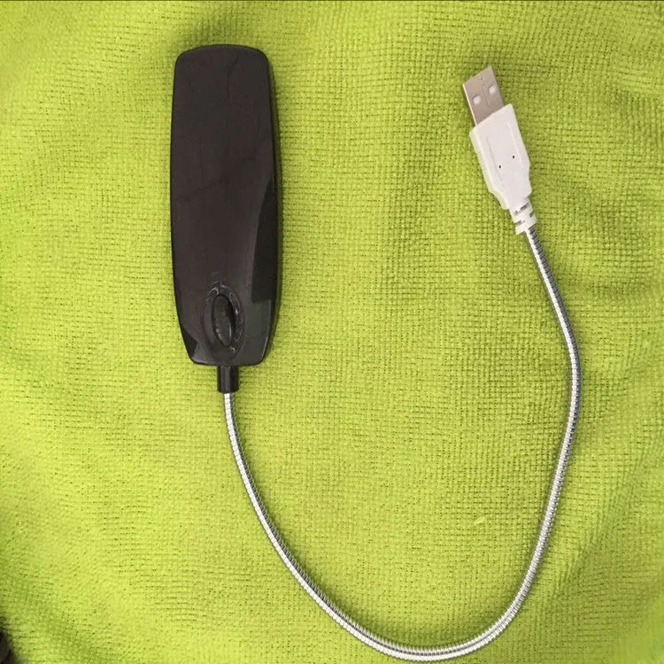 Black flexible USB desk lamp with gooseneck and clip, illuminated on a wooden surface.