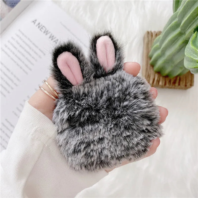 Soft pink silicone AirPods protective cover with rabbit ears design on a white earbud