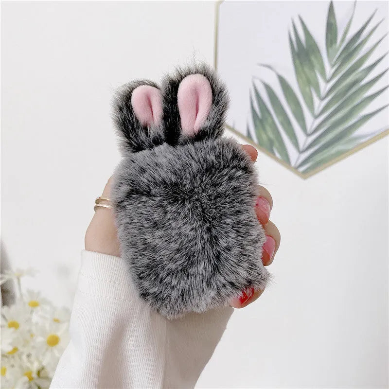 Soft pink silicone AirPods protective cover with rabbit ears design on a white earbud